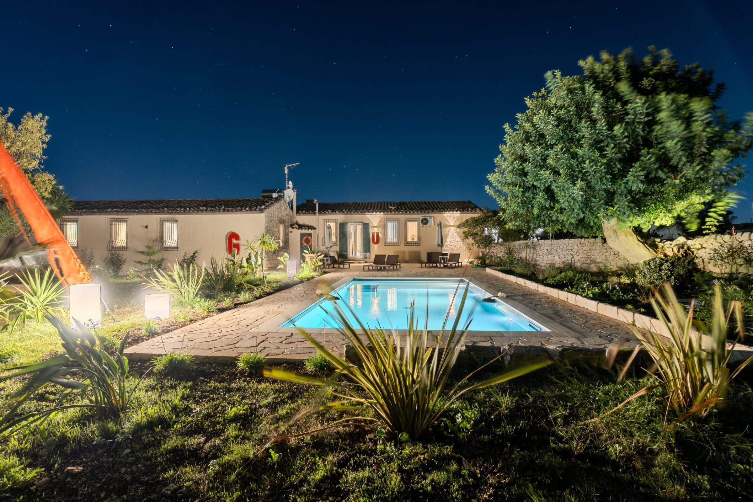 Wide night view of the illuminated pool and property